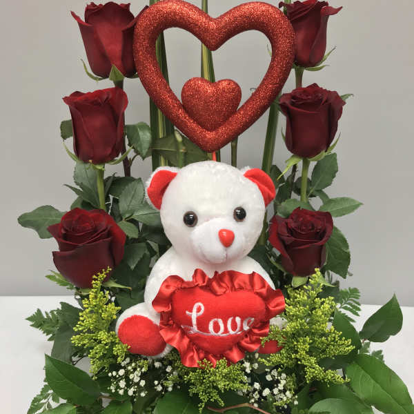Red roses arranged with a teddy bear and glittery heart decoration