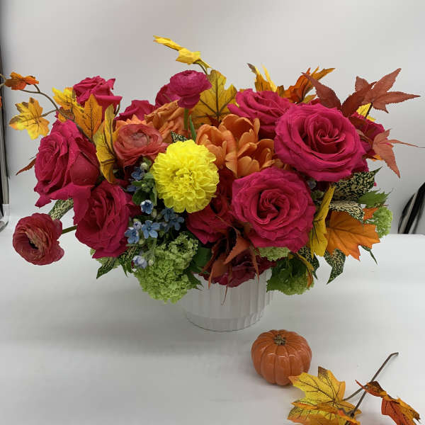 Bright mixed bouquet of pink roses and autumn leaves in a white vase