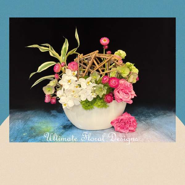Pink and white floral arrangement in a white bowl with a twig lattice accent