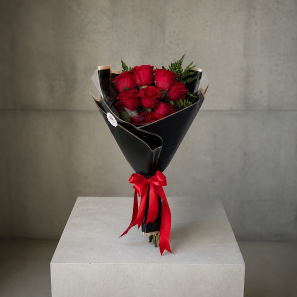 Bouquet of red roses wrapped in black paper with a red ribbon