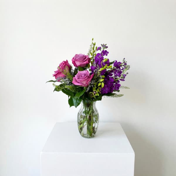 Pink and purple flower arrangement in a clear glass vase