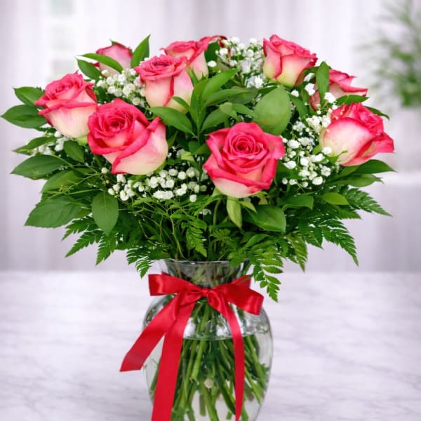 Pink roses in a glass vase with a red ribbon