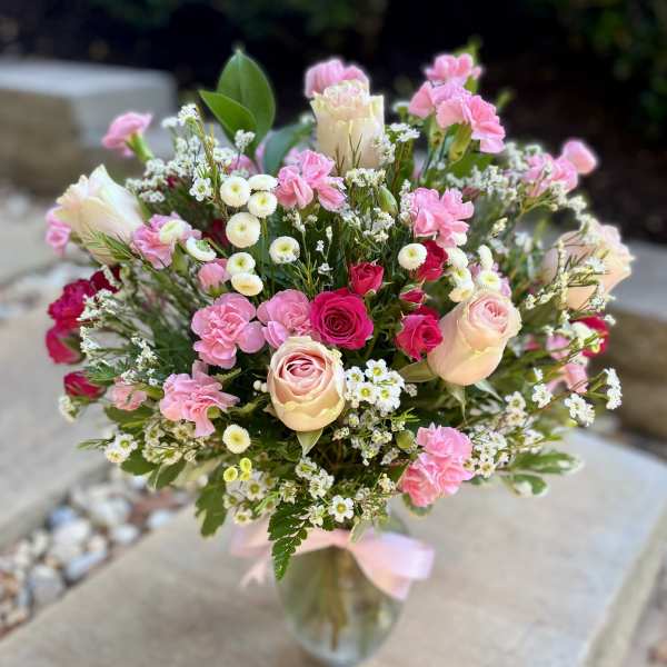 Pink and cream bouquet with roses and carnations in a glass vase