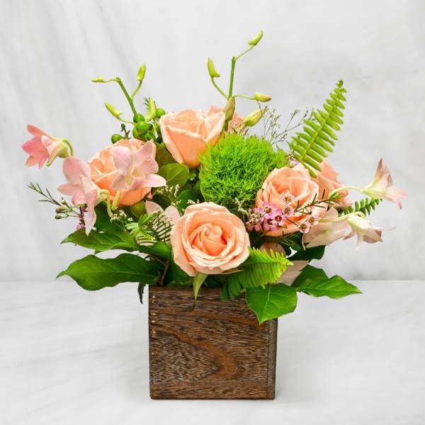Peach roses and pink orchids in a wooden box arrangement