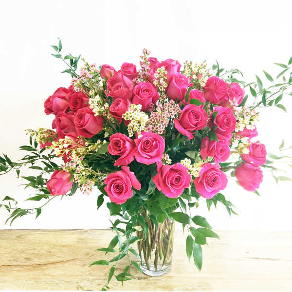 Pink roses arranged in a clear glass vase with small white filler flowers