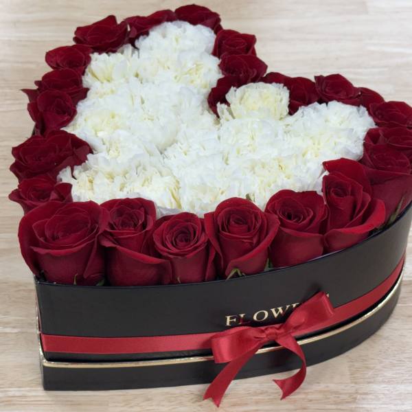 Heart-shaped box of red roses and white carnations with a red ribbon