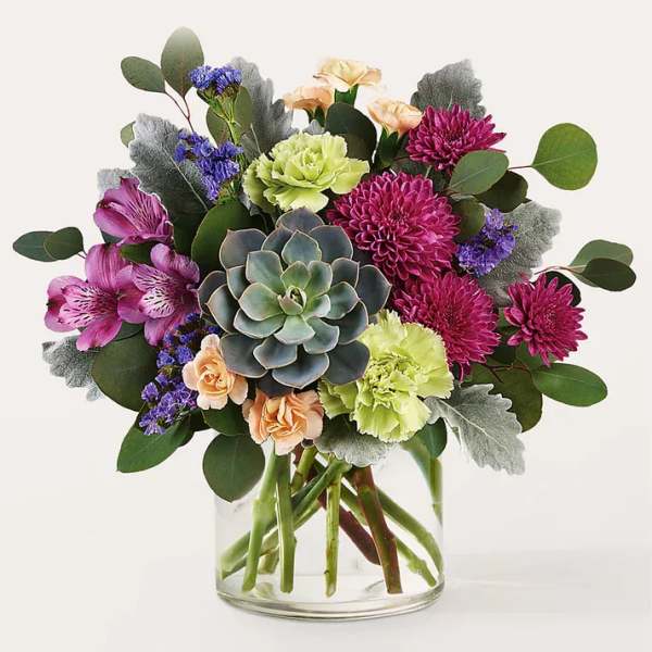 Mixed bouquet with succulents, carnations, and purple blooms in a glass vase