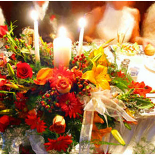 Low red, orange, and yellow floral centerpiece with candles on a formal banquet table