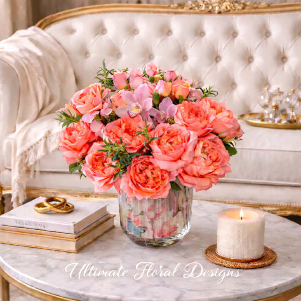 Pink and coral roses with orchids in a glass vase on a marble table