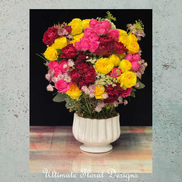 Bouquet of pink, red, and yellow roses in a white pedestal vase