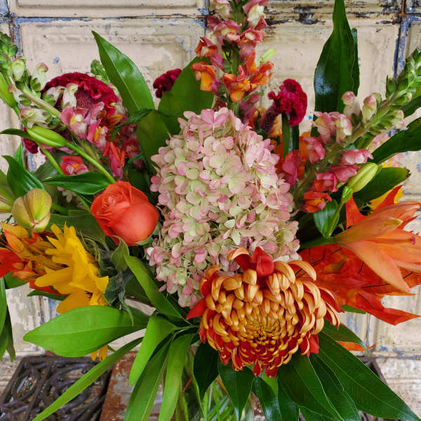 Mixed bouquet with pink hydrangea, orange roses, and tropical blooms