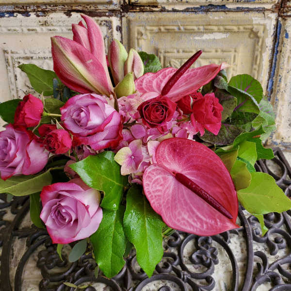 Pink roses and lilies arranged with green leaves