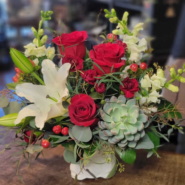 Bouquet of red roses and white lilies with a succulent in a white vase