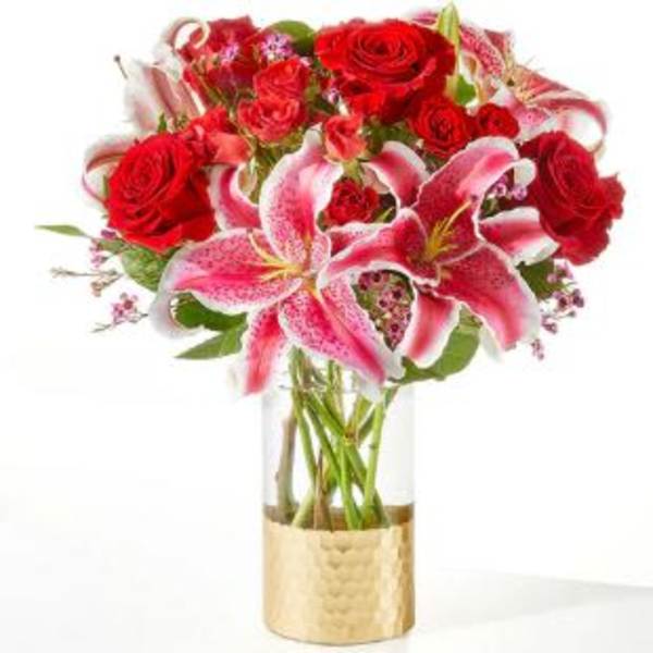 Bouquet of red roses and pink lilies in a clear glass vase