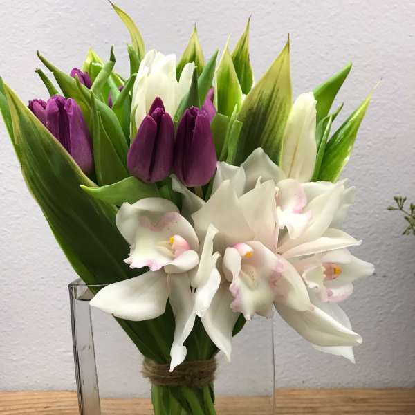 Purple tulips and white orchids in a clear glass vase