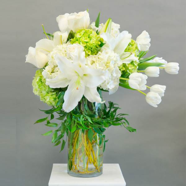 White lilies and tulips arranged in a glass vase