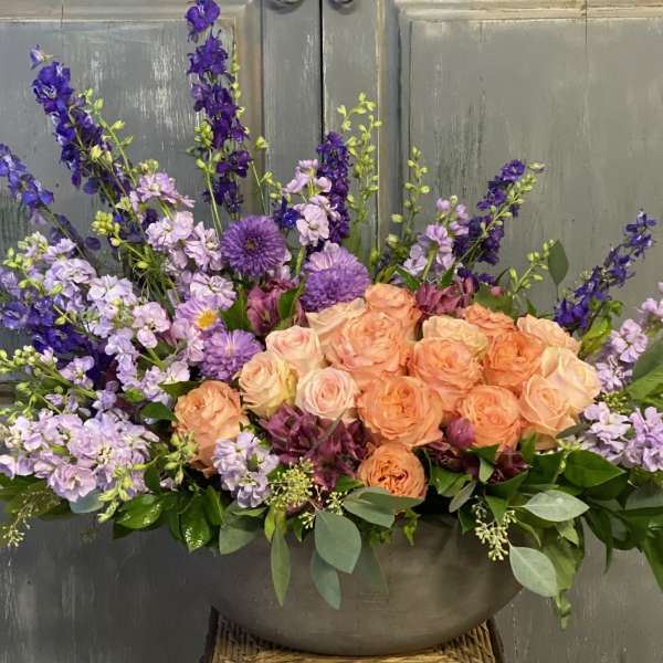 Peach roses and purple flowers in a low gray bowl