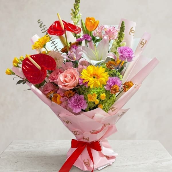 Mixed bouquet with roses, lilies, gerberas, and anthuriums in pink wrap