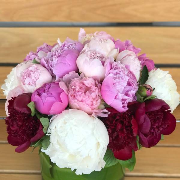 Pink and white peonies arranged in a green glass vase