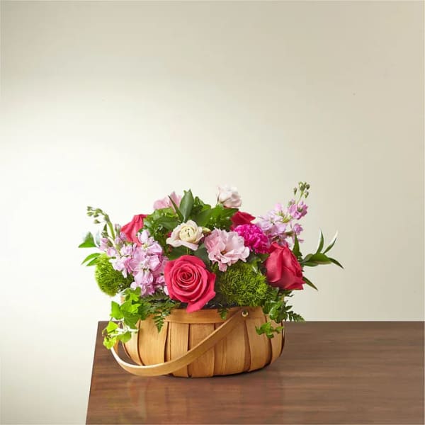 Pink and red flower arrangement in a woven basket