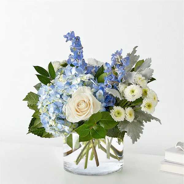 Blue hydrangeas and white roses in a clear glass vase