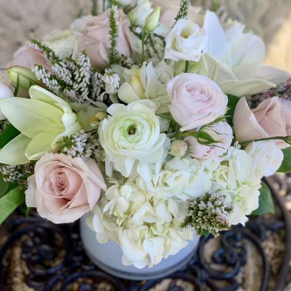 Blush and white bouquet with roses, lilies, and hydrangea in a vase