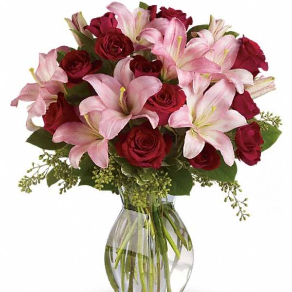 Bouquet of pink lilies and red roses in a clear glass vase