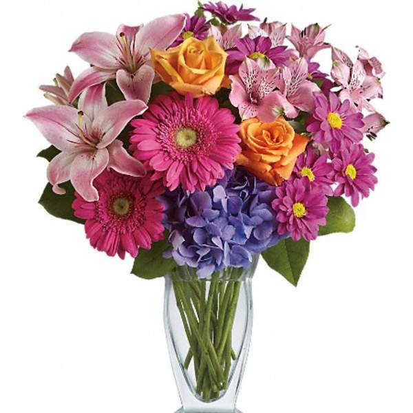 Mixed bouquet of lilies, roses, gerbera daisies, hydrangea, and daisies in a glass vase