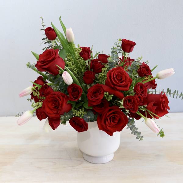 Red roses and pale tulips arranged in a white vase