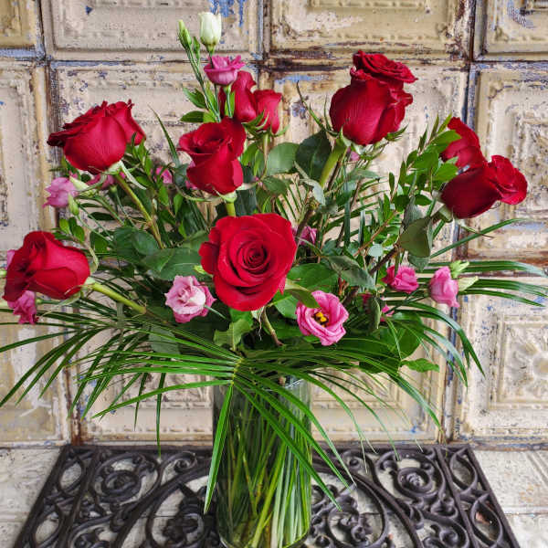 Red roses and pink lisianthus in a clear glass vase