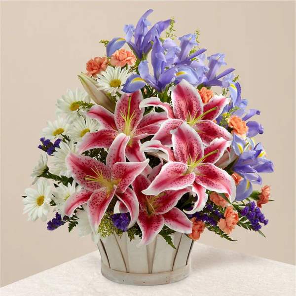 Bouquet of pink lilies, blue irises, and white daisies in a metal container