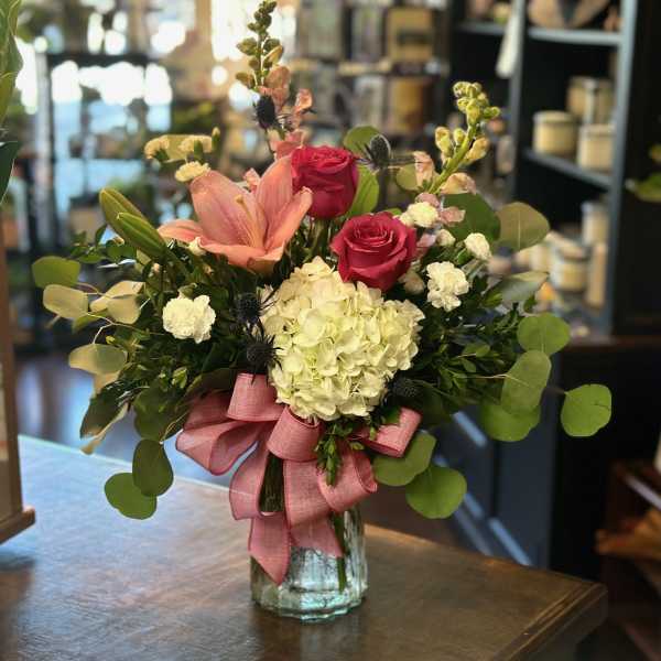 Pink roses and lilies in a glass vase with a pink ribbon