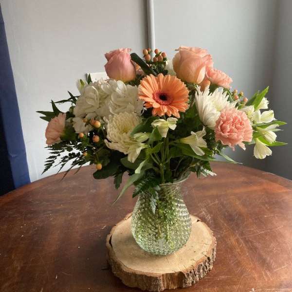 Mixed bouquet in a glass vase on a wood slice