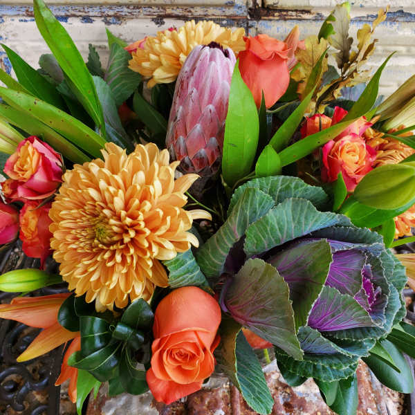Bouquet of orange roses, yellow chrysanthemums, and a pink protea