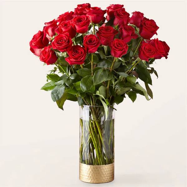 Bouquet of red roses in a clear glass vase with a gold base