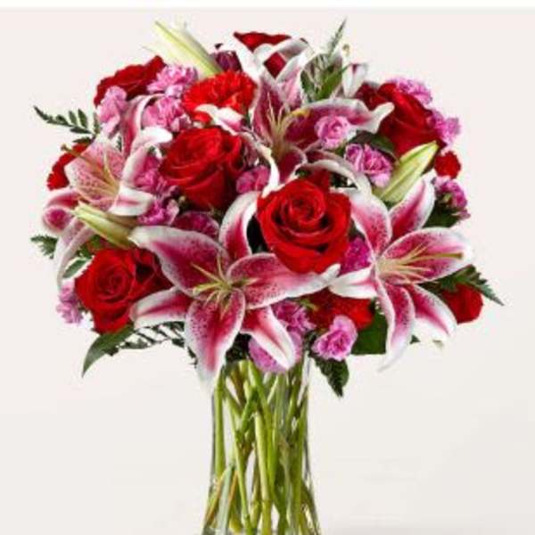 Bouquet of red roses and pink lilies in a clear glass vase