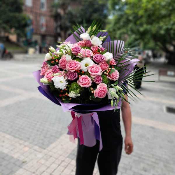 Large bouquet of pink and white roses with purple wrapping