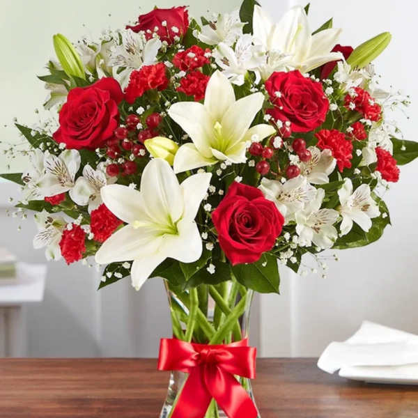 Red roses and white lilies in a glass vase with a red ribbon