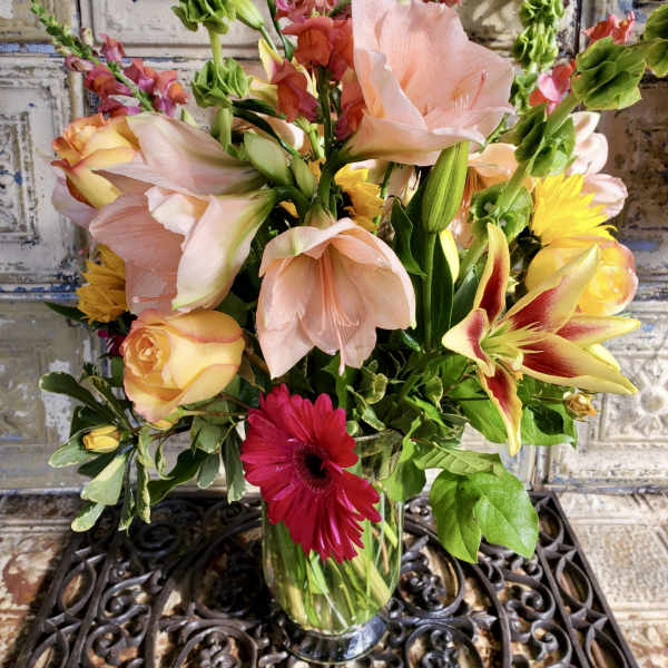 Mixed bouquet of lilies, roses, and a red gerbera daisy in a glass vase