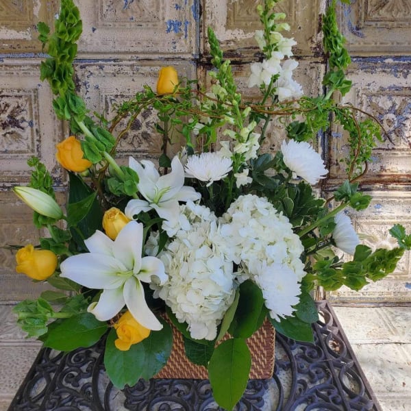 White lilies and yellow roses arranged in a wicker basket