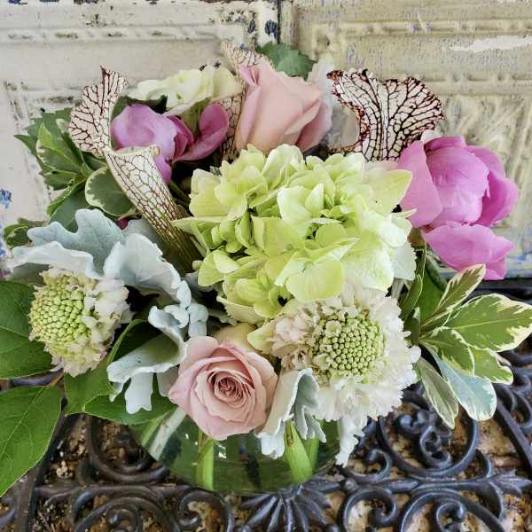 Mixed bouquet of pink roses, hydrangea, and white blooms in a glass vase