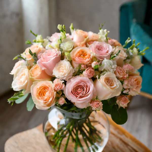 Bouquet of blush and peach roses in a clear glass vase