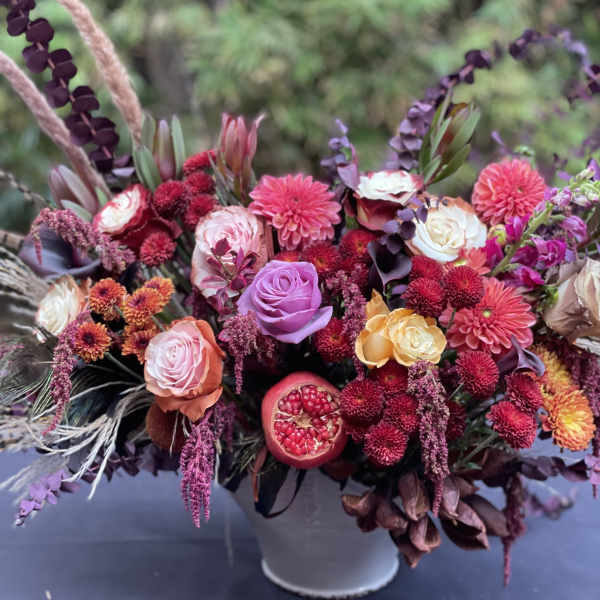 Mixed bouquet of pink, purple, and orange flowers in a white vase