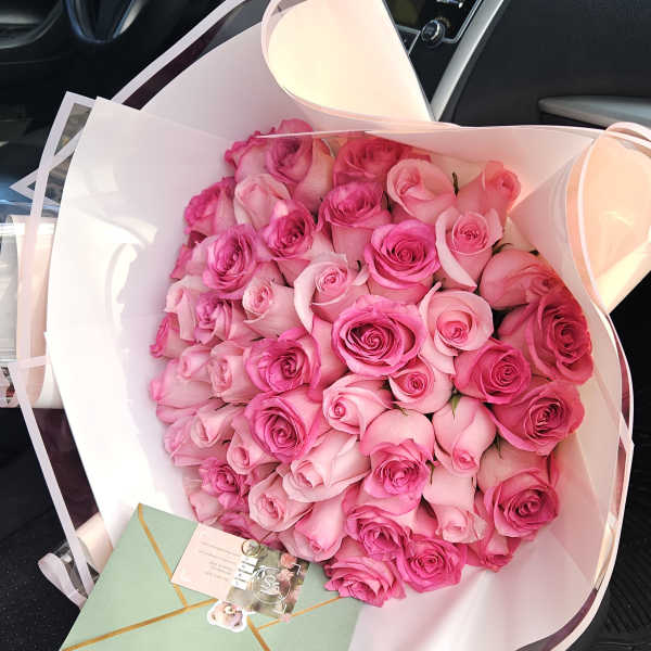 Bouquet of pink roses wrapped in white paper with a card