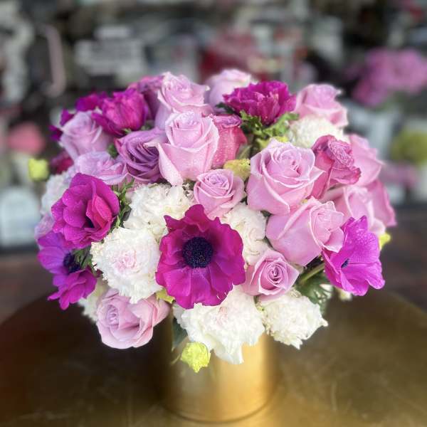 Pink and purple roses with white blooms in a gold vase