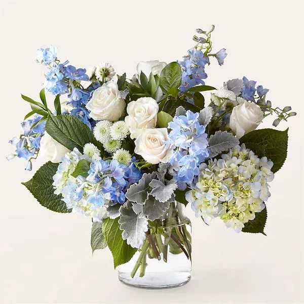 Blue and white flower arrangement in a clear glass vase
