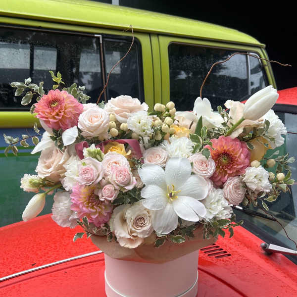 Pink and white floral arrangement in a round hatbox