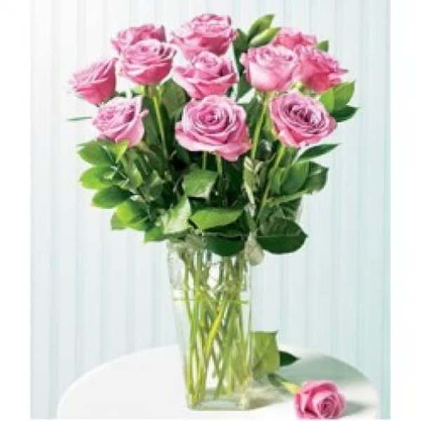 Pink roses in a clear glass vase with one rose on the table