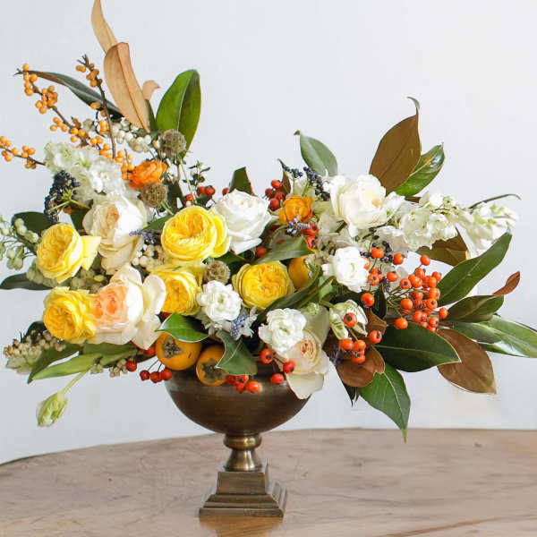 Yellow and white roses arranged in a bronze pedestal vase