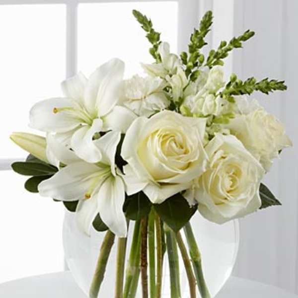 White roses and lilies arranged in a clear glass vase